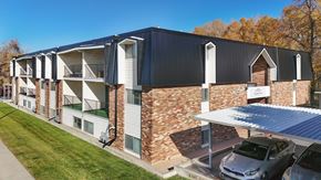 Sandy apartment for rent - A modern building with a black roof and a parking area in front.