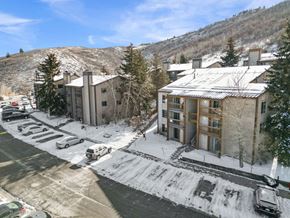 Park City condo for rent - A snowy parking lot with cars and a building in the background.