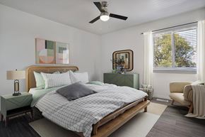 Ogden townhouse for rent - A bedroom with a bed, nightstand, chair, and a ceiling fan.