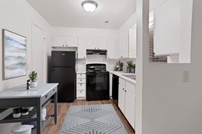 Sandy apartment for rent - a kitchen with white cabinetry and black appliances