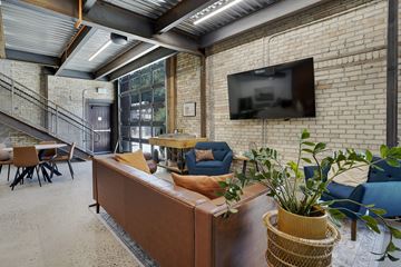 Logan apartment for rent - A living room with a couch, chairs, and a television mounted on a brick wall.