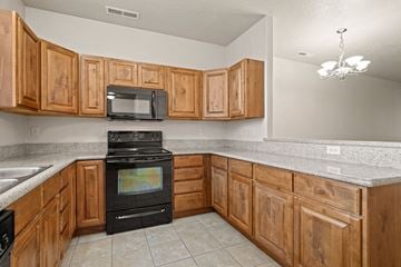 Provo apartment for rent - A kitchen with wooden cabinets and a black stove top oven.