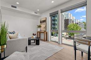 Salt Lake City apartment for rent - A living room with a grey couch, a coffee table, and a large window with a view of the street.