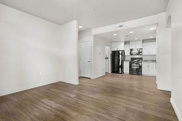 Midvale apartment for rent - A kitchen with white cabinets and a black fridge is visible from a living room.