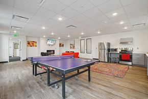 Salt Lake City apartment for rent - A ping pong table is in the middle of a room with a kitchen area in the background.