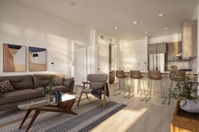 Salt Lake City apartment for rent - A modern living room with a grey sofa, wooden coffee table, and bar stools.
