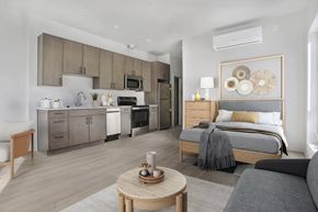 Salt Lake City apartment for rent - A modern bedroom with a large bed and a kitchen area in the background.