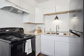 Tooele apartment for rent - a kitchen with white cabinets and black appliances and a sink