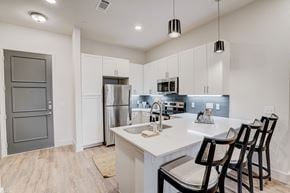 Lewisville apartment for rent - Modern kitchen with island seating and white cabinetry at The Mill Old Town Apartments, Lewisville, TX 75057