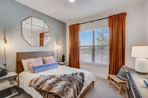 Lewisville apartment for rent - Bedroom with wooden bed frame and large mirror at The Mill Old Town Apartments, Lewisville, TX