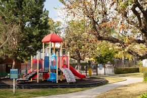 Claremont apartment for rent - A playground with a red and blue slide and a red roofed structure.