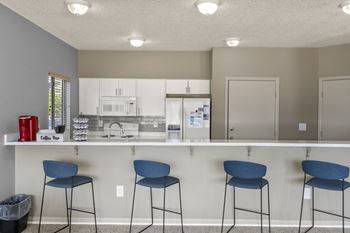 Clubhouse kitchen area with barstools and drink selection at horizon east in aurora.