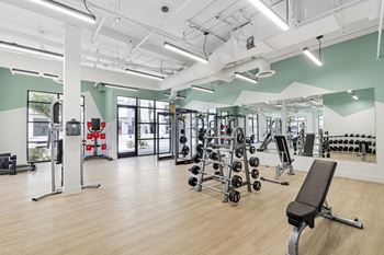 A gym with weights and other exercise equipment in a building with green walls
