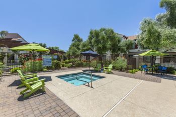 A swimming pool with green chairs and umbrellas in front of a house