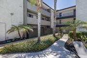 Reseda apartment for rent - a walkway with a bench and palm trees in front of an apartment building