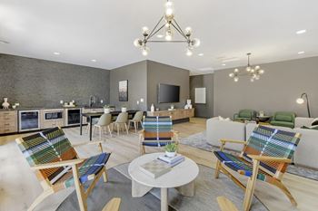 A living room with chairs and tables and a kitchen