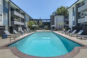 Reseda apartment for rent - a swimming pool with chaise lounge chairs and umbrellas in front of an apartment building