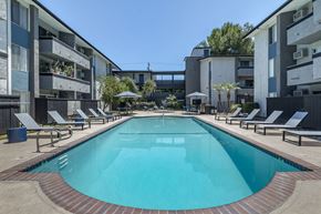 Reseda apartment for rent - a swimming pool with chaise lounge chairs and umbrellas in front of an apartment building