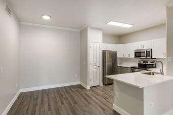 An empty kitchen with white cabinets and a stainless steel refrigerator