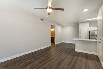 An empty living room with a ceiling fan and a kitchen