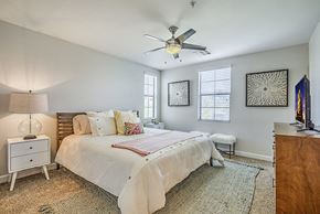 Las Vegas apartment for rent - Dog-Friendly Apartments in Spring Valley, NV - The Michael B Townhomes and Flats - Bright Bedroom With Ceiling Fan, Wood Bed, Two Windows With Blinds, and Dresser With Television.