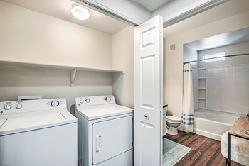 A washer and dryer in a room with a shower and toilet