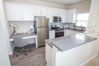 A kitchen with white cabinets and a gray counter top