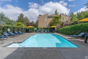 Bellevue apartment for rent - A large swimming pool surrounded by a black fence and lounge chairs. at Kelsey Ridge, Bellevue, 98005