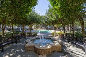 Plano apartment for rent - A fountain in the middle of a park surrounded by benches and trees.