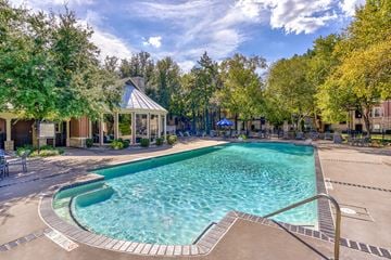 Plano apartment for rent - A large outdoor swimming pool surrounded by trees and a gazebo.