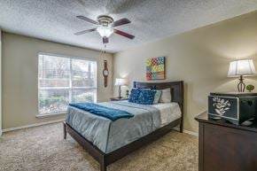 Dallas apartment for rent - A bedroom with a bed, nightstand, and window.