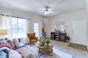 Dallas apartment for rent - A living room with a brown chair and a white ceiling fan.
