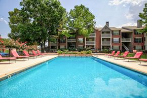 Tulsa apartment for rent - A swimming pool surrounded by red chairs and trees.