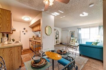 Las Vegas apartment for rent - A dining table with a yellow plate on it is in the middle of a kitchen and living room.