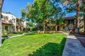 Tucson apartment for rent - A row of houses with green lawns and trees in front.
