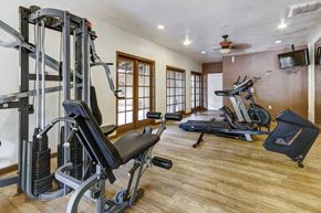 Tucson apartment for rent - A home gym with a variety of equipment including a treadmill, weights, and a bench press.