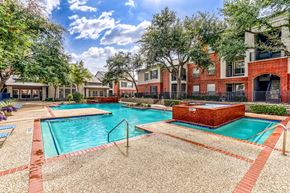 Dallas apartment for rent - A swimming pool surrounded by a brick patio and trees.