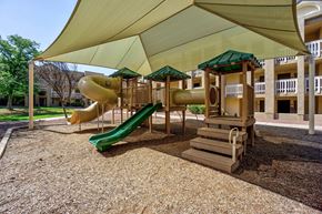 Tucson apartment for rent - A playground with a green slide and a yellow and green canopy.
