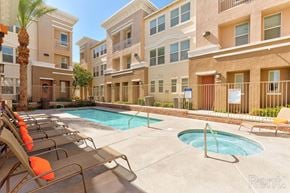 Henderson townhouse for rent - A pool area with sun loungers and a fence in front of apartment buildings.