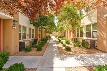 Henderson townhouse for rent - A row of houses with trees and bushes in front.