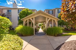 Lawrence apartment for rent - A gazebo-like structure is in the middle of a walkway between two buildings at Prairie Commons - 55+ Senior Community Apartments, Lawrence, Kansas