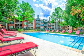 Tulsa apartment for rent - Outdoor swimming pool with red lounge chairs at Greenbriar Apartments, Tulsa, OK
