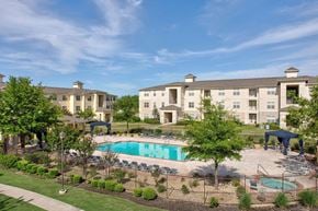 Tulsa apartment for rent - A large apartment complex with a pool and a fenced in area with trees.