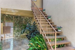 Los Angeles apartment for rent - A wooden staircase with a glass balustrade leads up to a door.
