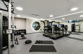 Los Angeles apartment for rent - two treadmills and weights in a gym with a round mirror on the wall