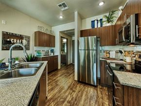 Mesa apartment for rent - kitchen with stainless steel double sink and stainless steel refrigerator.  Beautiful modern cabinets line kitchen walls and surround black range. at Craft at Gilbert and Baseline Apartments, Arizona,