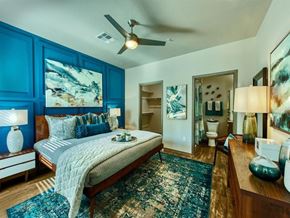 Mesa apartment for rent - master bedroom with queen size bed and blue accent colored wall behind it. A door leads to the master bathroom and a second door shows the walk-in closet at Craft at Gilbert and Baseline Apartments, A