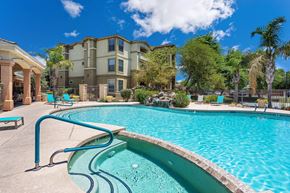 Mesa apartment for rent - A swimming pool in front of a building with a blue sky in the background. at Superstition Canyon Apartments, Mesa, Arizona