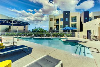 A swimming pool with a yellow sun lounger and a blue umbrella.