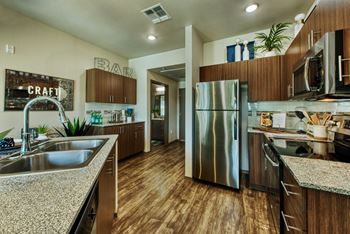 A modern kitchen with wooden cabinets and a stainless steel refrigerator.